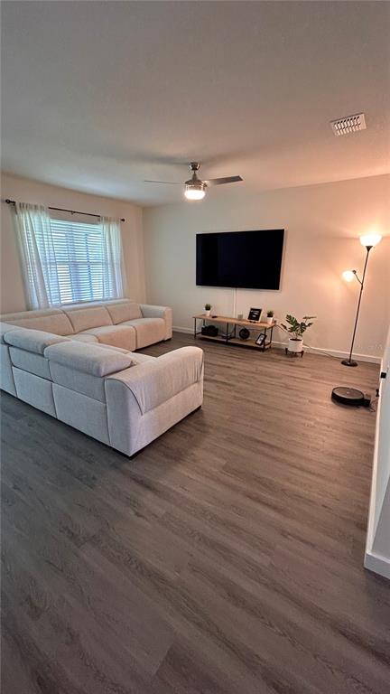 A living room features a large sectional sofa, a wall-mounted television, and wood-look flooring — 3919 MALAWI TRAIL, ST CLOUD, FL