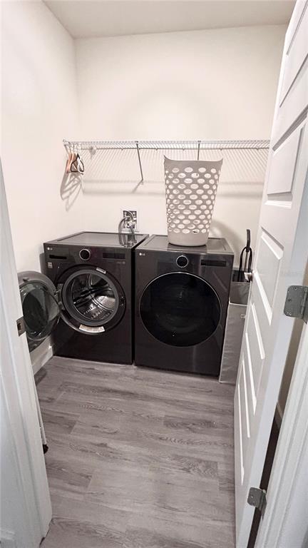 A laundry room features dark gray front-loading appliances, a white laundry basket, and wood-look flooring — 3919 MALAWI TRAIL, ST CLOUD, FL