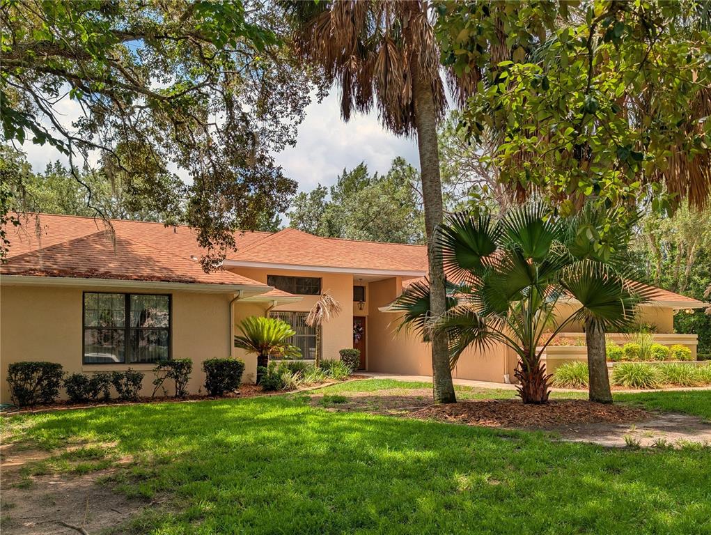 A single-story house with a tan exterior, orange roof, and palm trees in the yard — 4023 N RINGWOOD CIRCLE, HERNANDO, FL