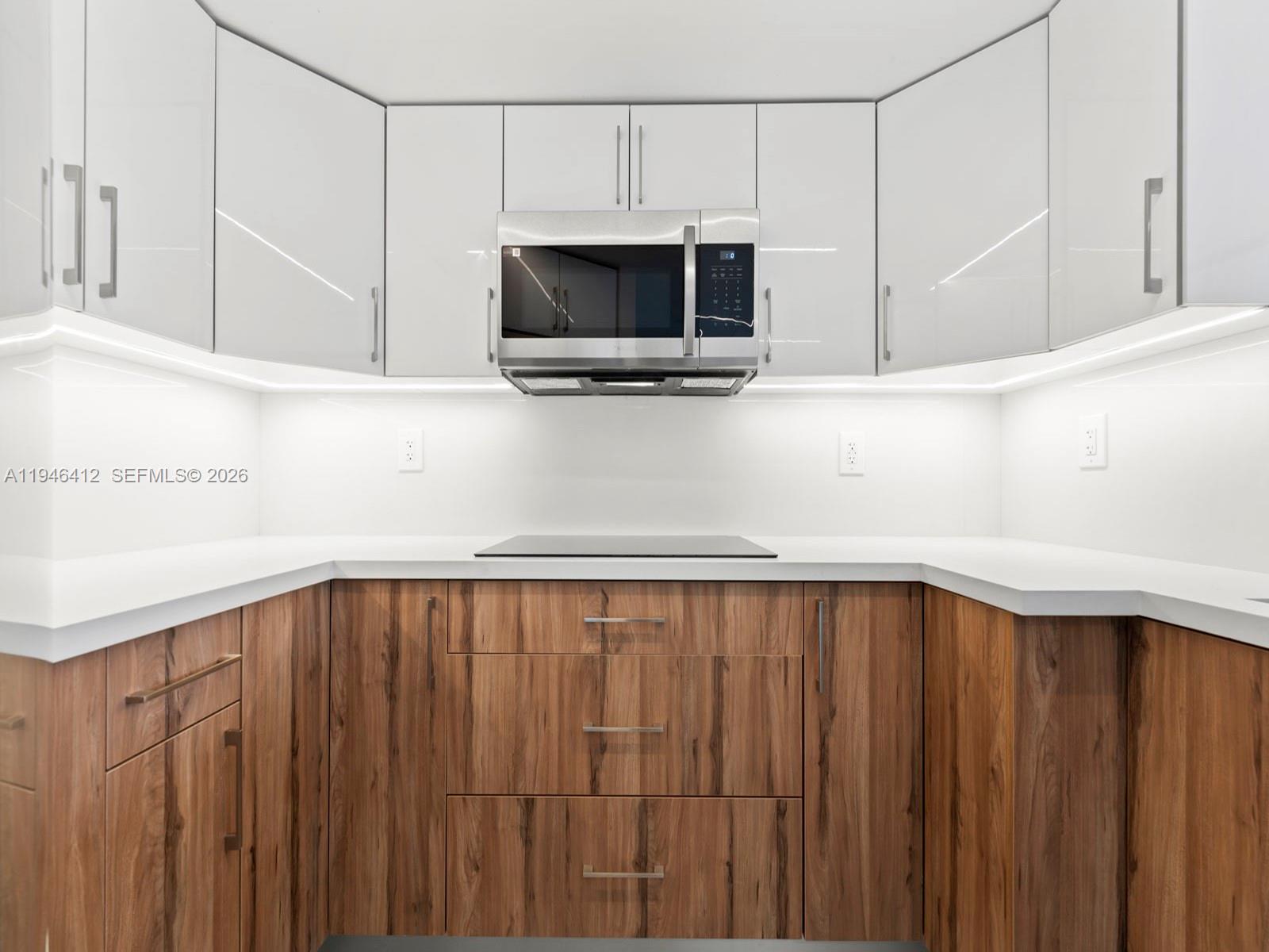 A modern kitchen features white upper cabinets, wood-grain lower cabinets, and a white countertop — 8215 SW 152nd Ave # 308, Miami FL 33193, MIAMI, FL