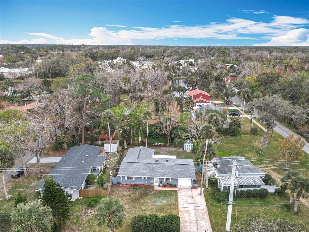 An aerial view shows a residential neighborhood with several houses, trees, and a small pond — 608 POWERS AVENUE, PORT ORANGE, FL