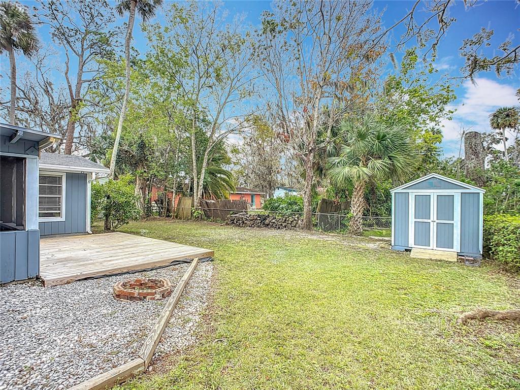 A backyard features a wooden deck, a gravel area with a fire pit, and a shed — 608 POWERS AVENUE, PORT ORANGE, FL