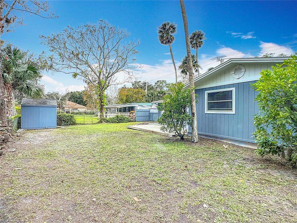 A blue house with a matching shed sits in a grassy backyard with palm trees — 608 POWERS AVENUE, PORT ORANGE, FL