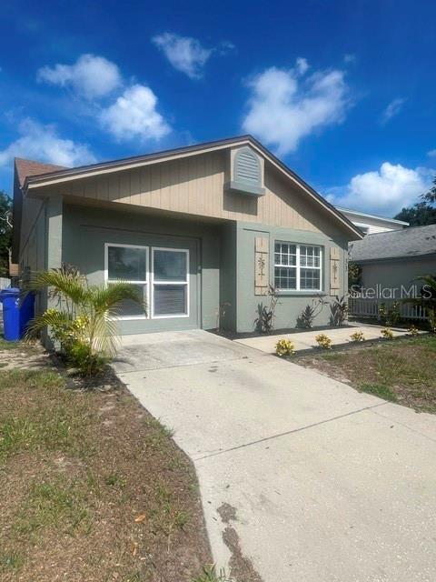 The exterior of a single-story house features green siding, a concrete driveway, and a gable roof — 1100 LOWRY AVENUE UNIT 33, LAKELAND, FL