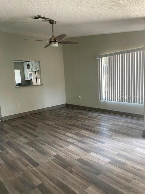 An empty room features wood-look flooring, a ceiling fan, and a pass-through window to the kitchen — 1100 LOWRY AVENUE UNIT 33, LAKELAND, FL