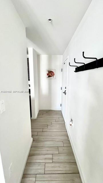 A narrow hallway features light wood-look tile flooring, white walls, and a black coat rack — 481 NE 29th St # 502, Miami FL 33137, MIAMI, FL