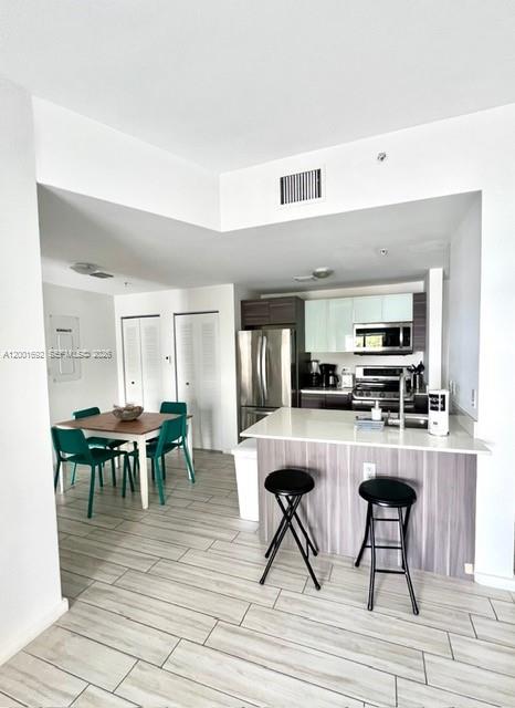 A modern kitchen with stainless steel appliances and a breakfast bar overlooks a dining area — 481 NE 29th St # 502, Miami FL 33137, MIAMI, FL