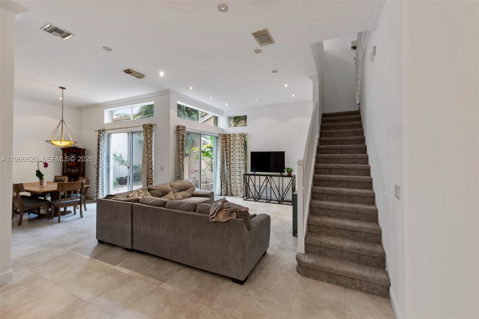 A living room and dining area feature tile floors, a staircase, and large sliding glass doors — 1104 Redwood St, Hollywood FL 33019, HOLLYWOOD, FL