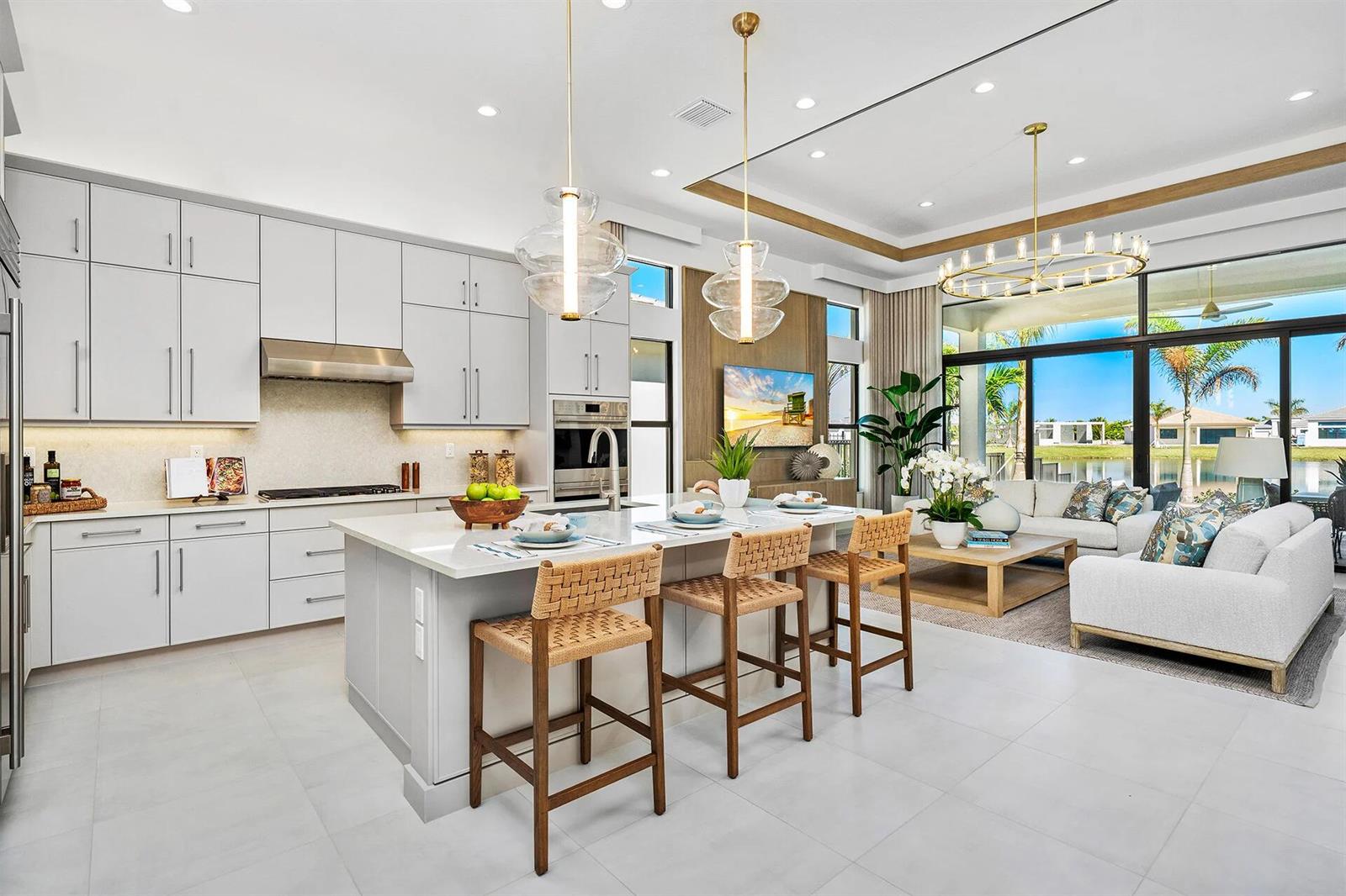 A modern open-concept kitchen and living area with white cabinetry, a large island, and patio — 9124 Red Robin Lane, Boynton Beach FL 33473, BOYNTON BEACH, FL