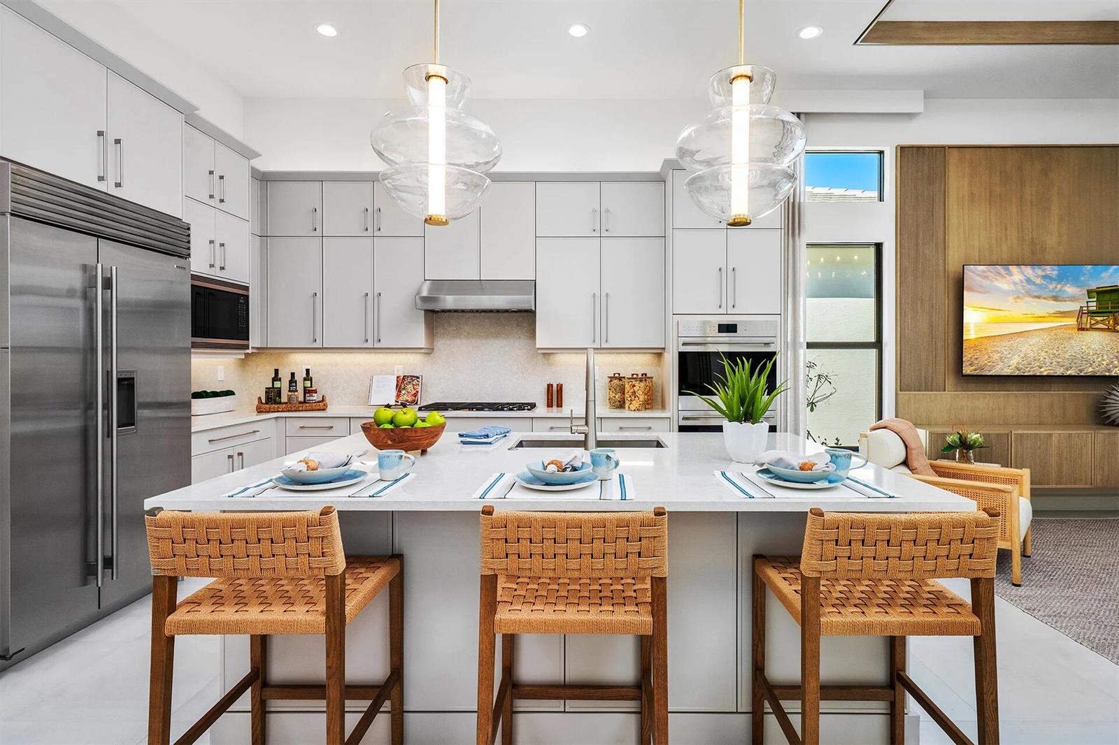 A modern kitchen features a large white island, woven bar stools, and light gray cabinetry — 9124 Red Robin Lane, Boynton Beach FL 33473, BOYNTON BEACH, FL