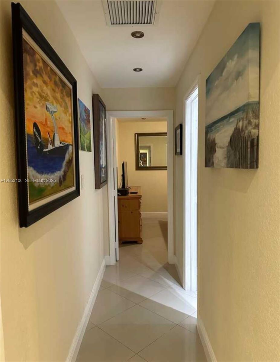 A hallway with tiled floors leads to an open doorway showing a room with furniture — MIAMI, FL