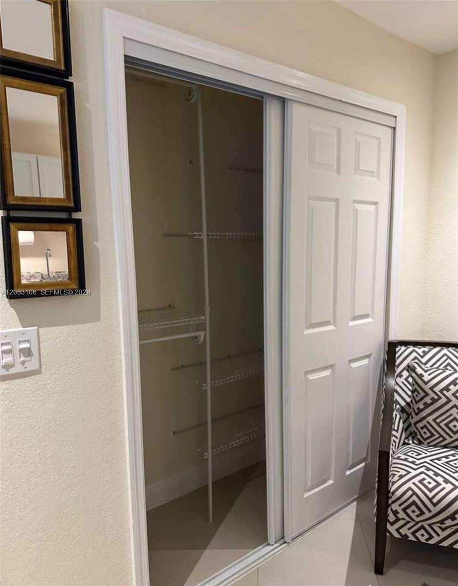 A closet with white wire shelving sits beside a wall featuring three framed mirrors — MIAMI, FL
