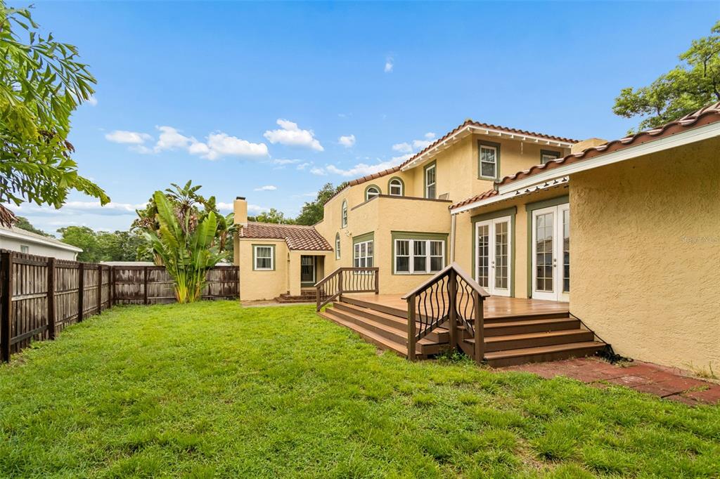 A tan stucco house with a wooden deck and a fenced backyard under a blue sky — 2518 GRANADA CIRCLE E, ST PETERSBURG, FL