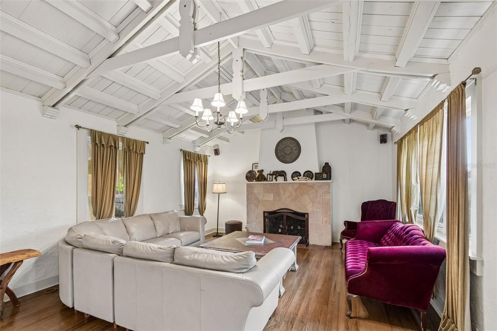 A living room features a vaulted white ceiling with exposed beams, a stone fireplace, and furniture — 2518 GRANADA CIRCLE E, ST PETERSBURG, FL