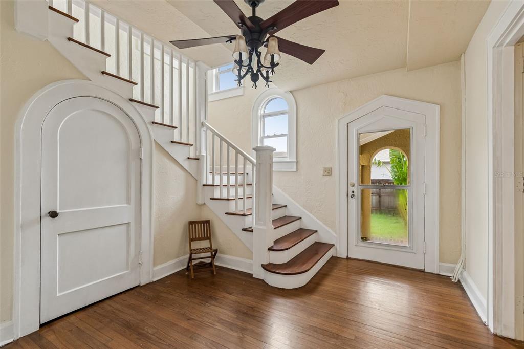 An entryway features a wooden staircase, arched doorways, a ceiling fan, and hardwood flooring — 2518 GRANADA CIRCLE E, ST PETERSBURG, FL