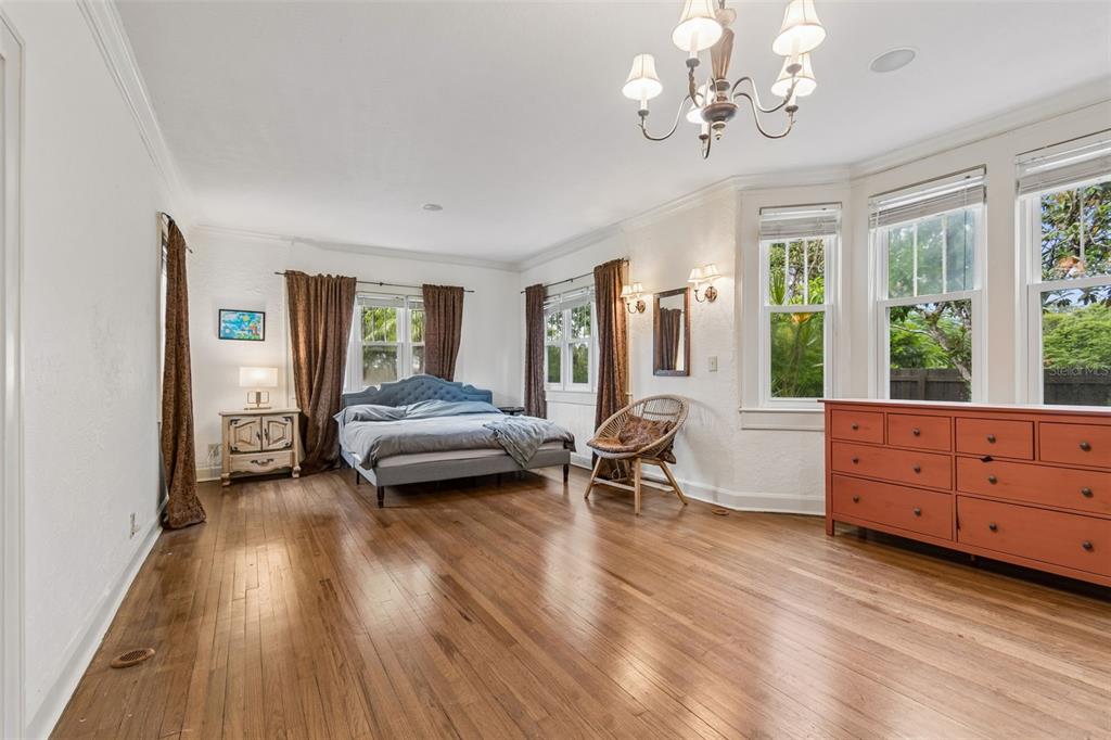 A bedroom with hardwood floors, a blue tufted bed, a chandelier, and a red dresser — 2518 GRANADA CIRCLE E, ST PETERSBURG, FL