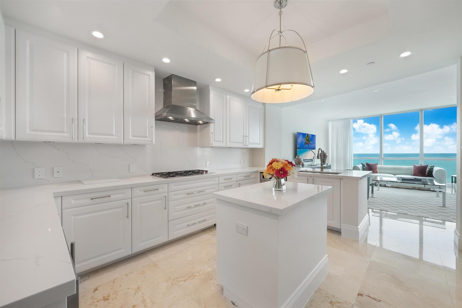 A bright, modern white kitchen features marble countertops, stainless steel appliances, and an ocean view — 10295 Collins Avenue # 2203, Bal Harbour FL 33154, BAL HARBOUR, FL