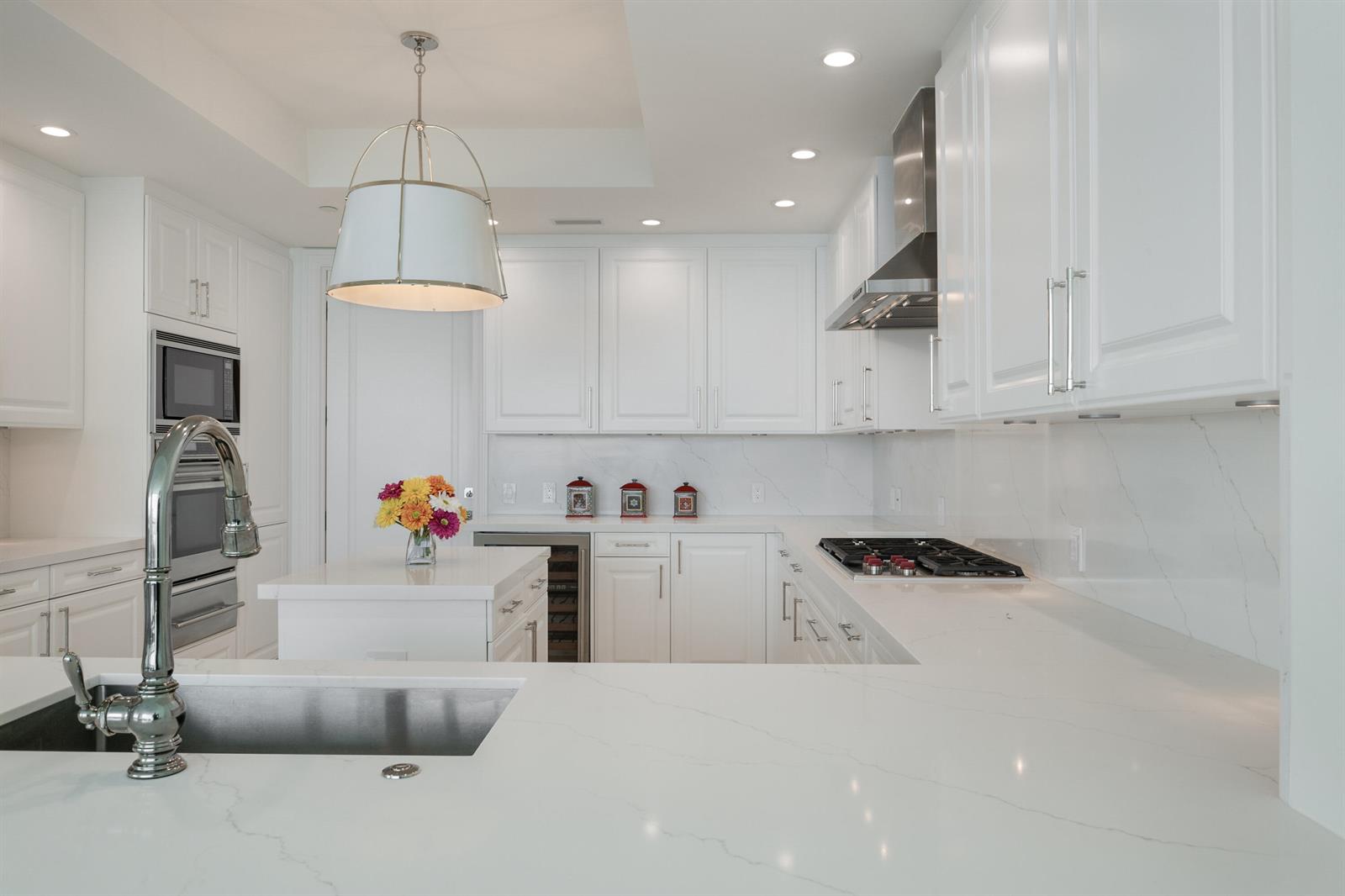 A bright white kitchen features quartz countertops, stainless steel appliances, and a central island — 10295 Collins Avenue # 2203, Bal Harbour FL 33154, BAL HARBOUR, FL