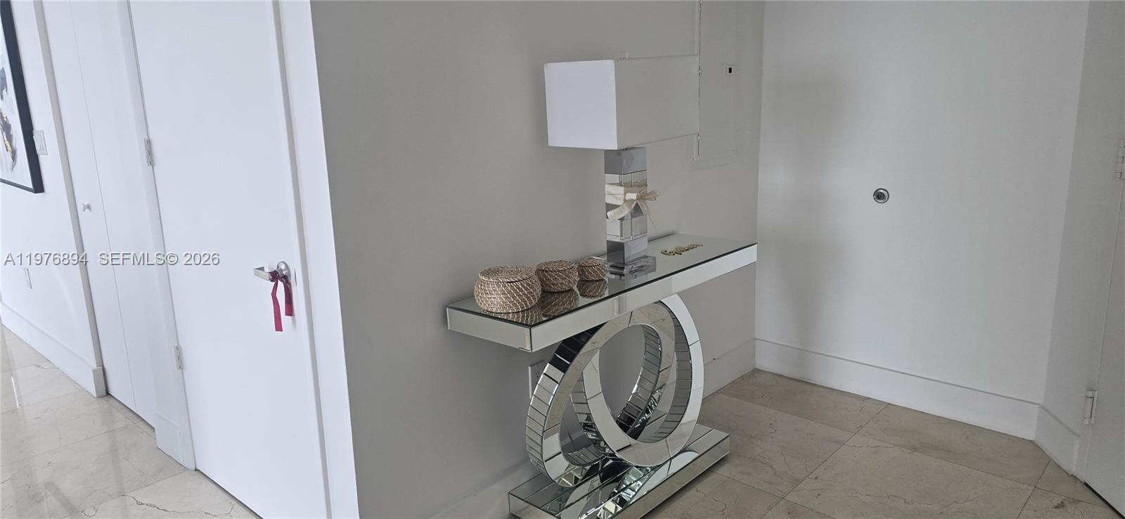 A mirrored console table with a lamp sits against a white wall in a hallway — 495 Brickell Ave # 5310, Miami FL 33131, MIAMI, FL