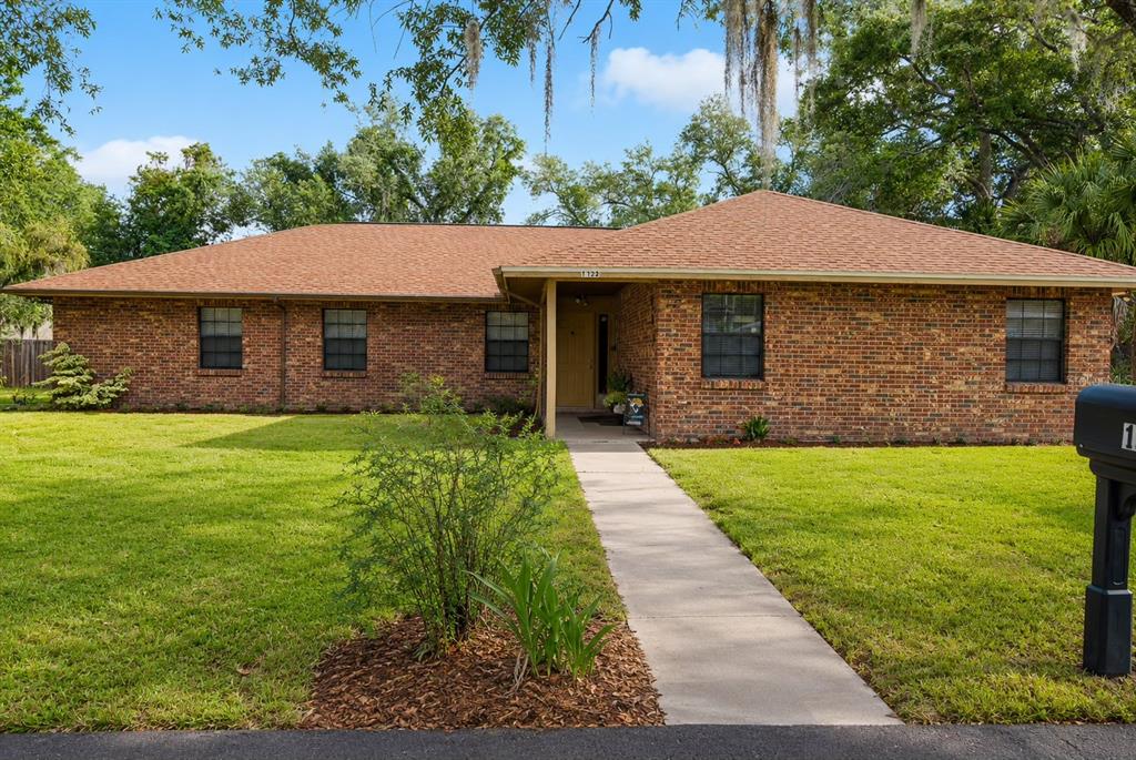 A single-story brick house with a brown shingled roof and a concrete walkway — 1022 LAMPLIGHTER LANE, LAKELAND, FL