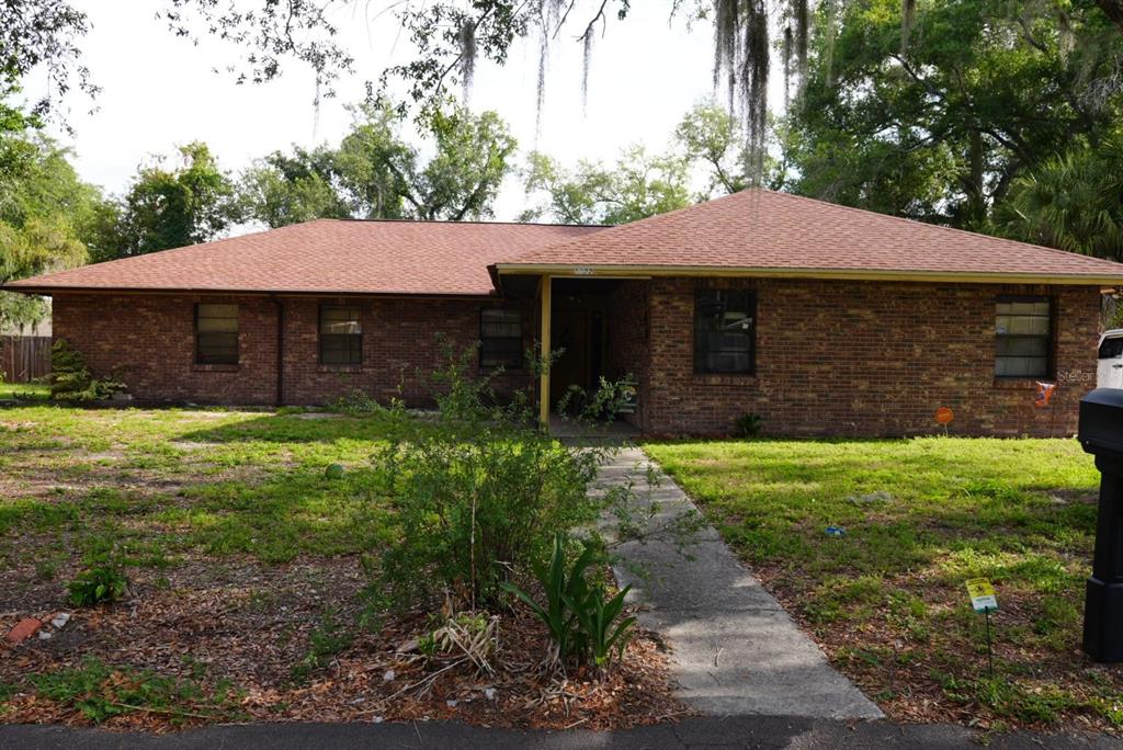 A single-story brick house with a brown shingled roof and a concrete walkway — 1022 LAMPLIGHTER LANE, LAKELAND, FL