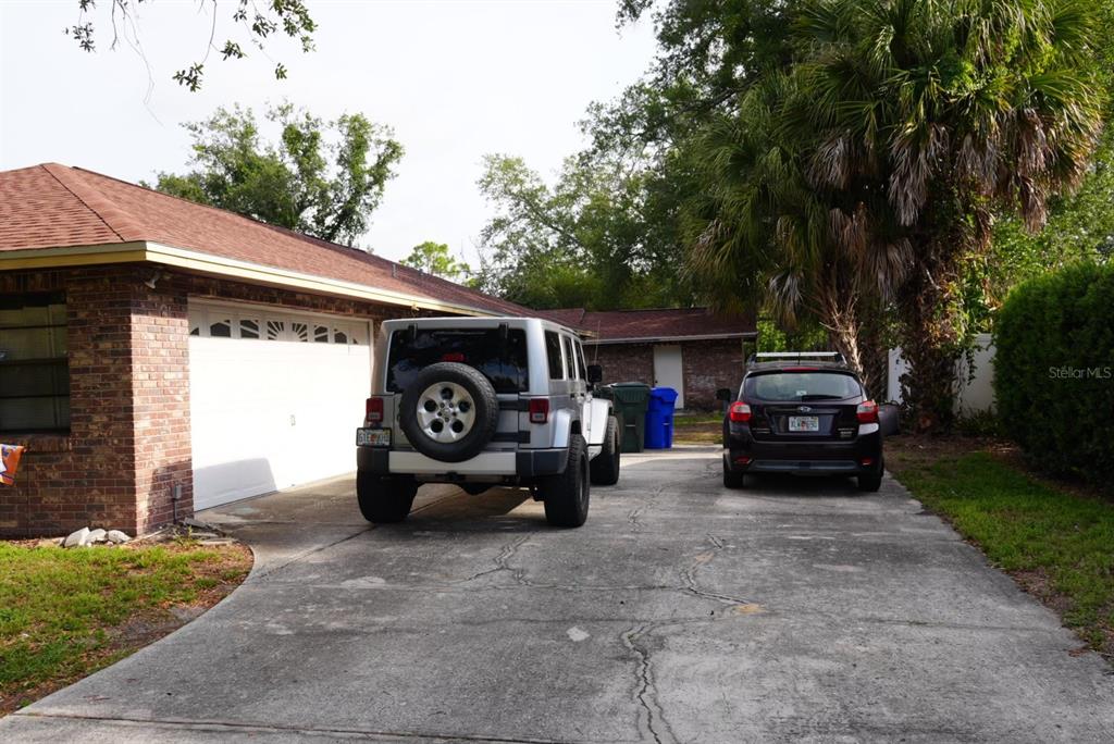 A driveway with a silver Jeep and a black SUV parked in front of a house — 1022 LAMPLIGHTER LANE, LAKELAND, FL
