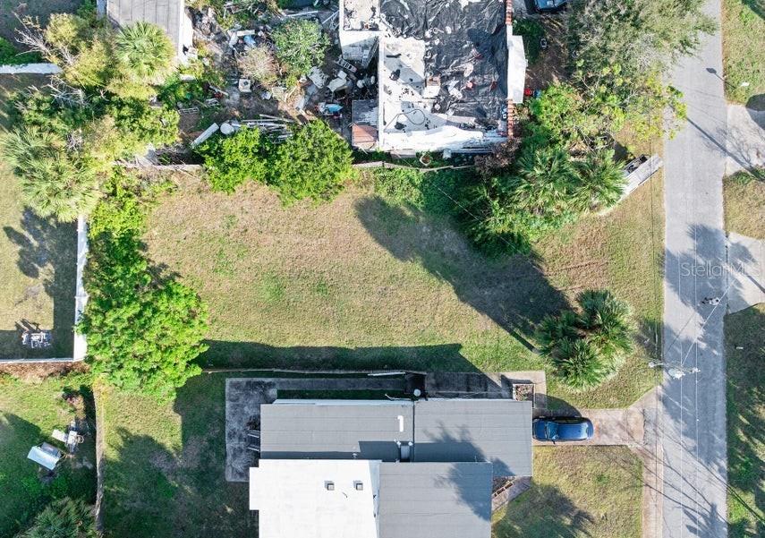 An aerial view shows a vacant grassy lot situated between two residential properties — 339 MANHATTAN AVENUE, DAYTONA BEACH, FL