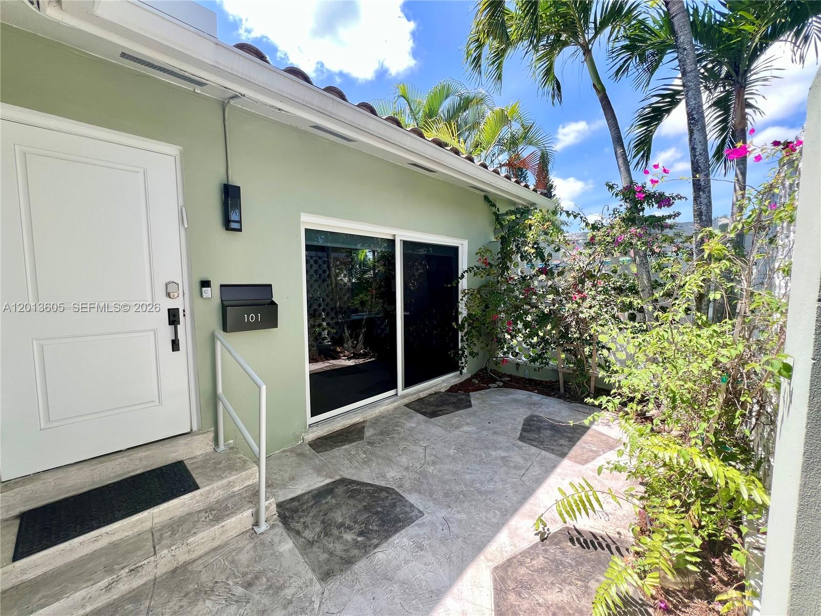 An exterior view shows a light green building entrance with a white door and sliding glass doors — 101 SW 58th Ave # 101, Plantation FL 33317, PLANTATION, FL