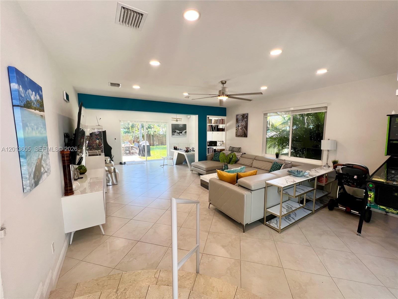 A spacious living room features light tile floors, a sectional sofa, and a teal accent wall — 101 SW 58th Ave # 101, Plantation FL 33317, PLANTATION, FL