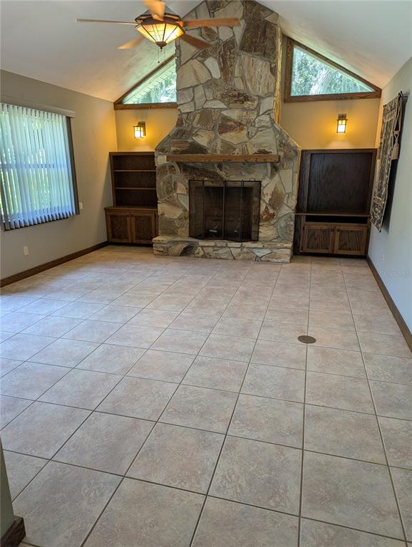 A living room features a large stone fireplace, built-in wooden cabinets, and tile flooring — 308 TRUDGEON DRIVE, NEW SMYRNA BEACH, FL