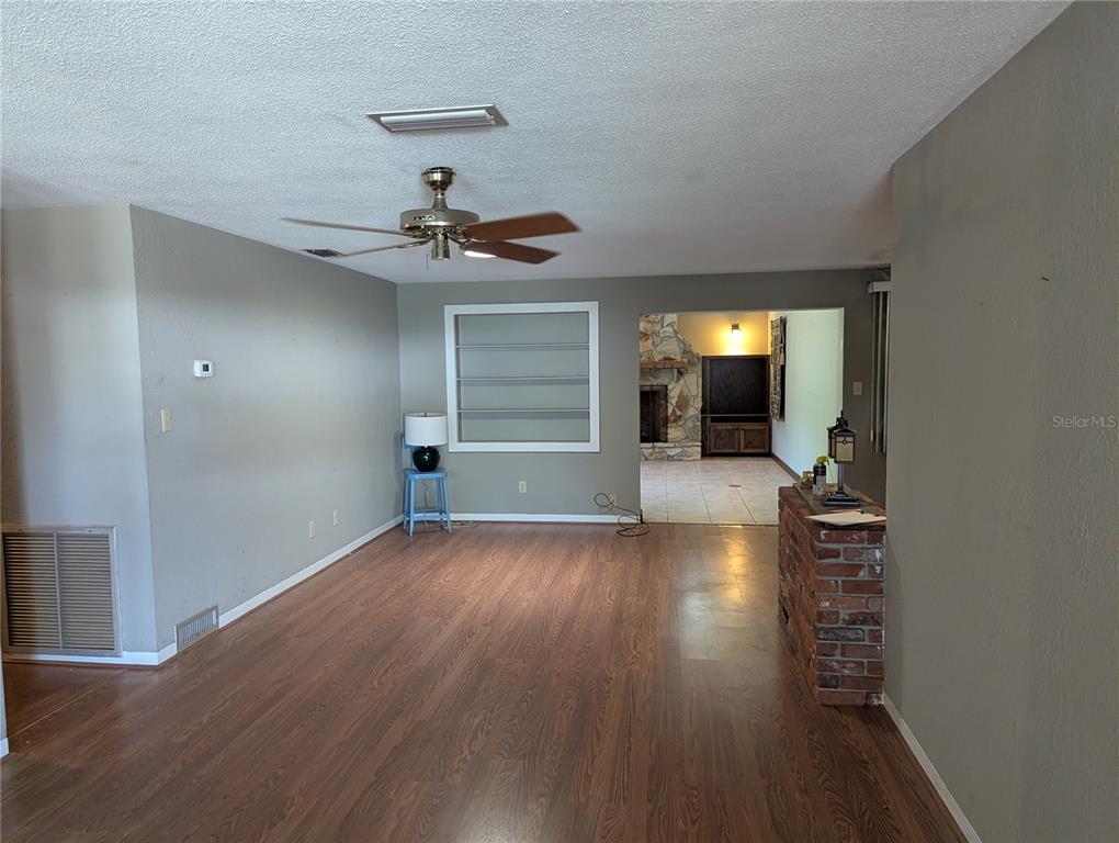A living room with wood-look flooring, a ceiling fan, and a brick partition wall — 308 TRUDGEON DRIVE, NEW SMYRNA BEACH, FL