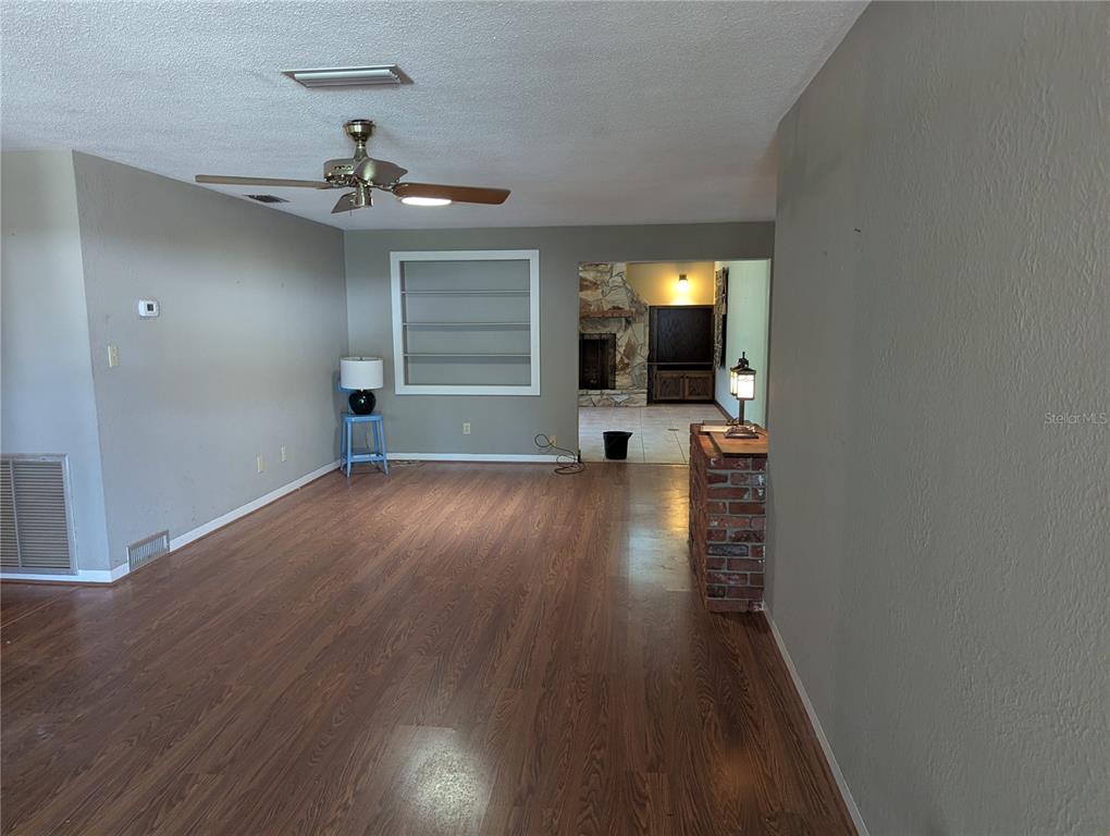 A living room features wood-look flooring, a ceiling fan, and a brick partition wall — 308 TRUDGEON DRIVE, NEW SMYRNA BEACH, FL