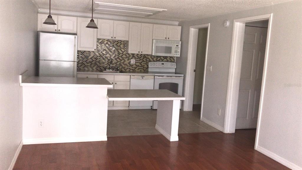 A kitchen with white cabinets, a mosaic tile backsplash, and a peninsula counter — 4073 E MICHIGAN STREET UNIT 4073, ORLANDO, FL