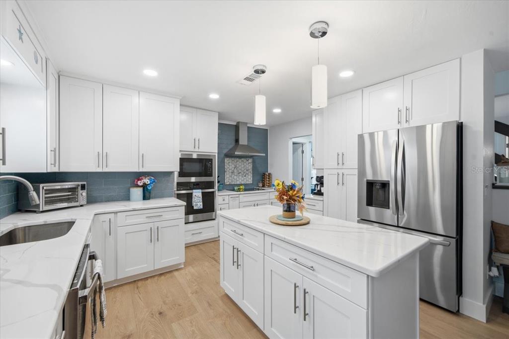 A modern kitchen features white cabinets, a marble-topped island, stainless steel appliances, and blue backsplash — 5214 S RIVERVIEW CIRCLE, HOMOSASSA, FL