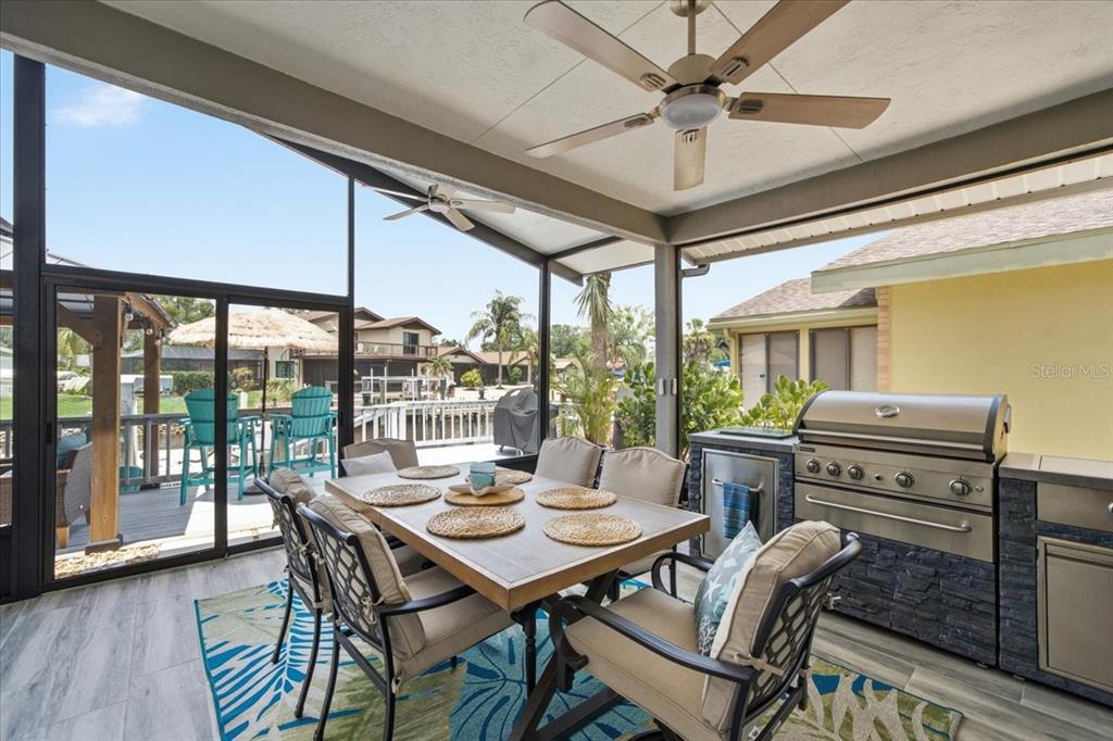 A covered outdoor patio features a dining table, a built-in grill, and a screened enclosure — 5214 S RIVERVIEW CIRCLE, HOMOSASSA, FL