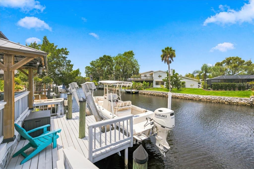 A boat is docked at a wooden deck with a turquoise chair along a canal — 5214 S RIVERVIEW CIRCLE, HOMOSASSA, FL