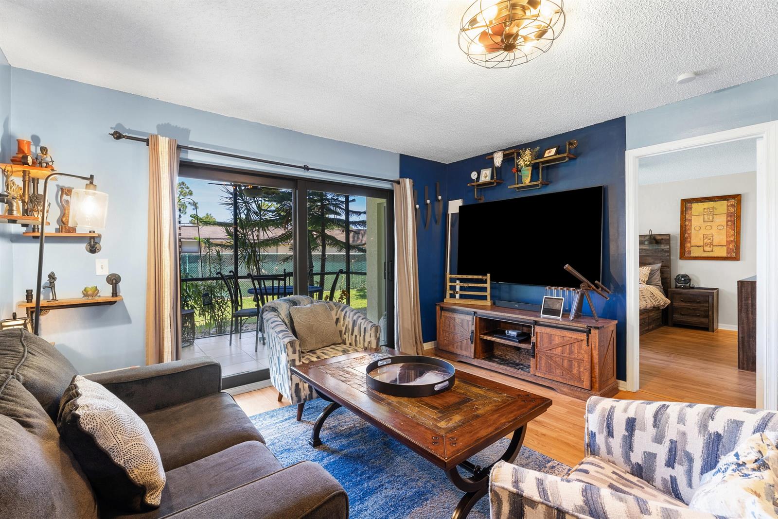 A living room features a dark blue accent wall, a television, and sliding glass doors — 1201 SE Parkview Place # G4, Stuart FL 34994, STUART, FL