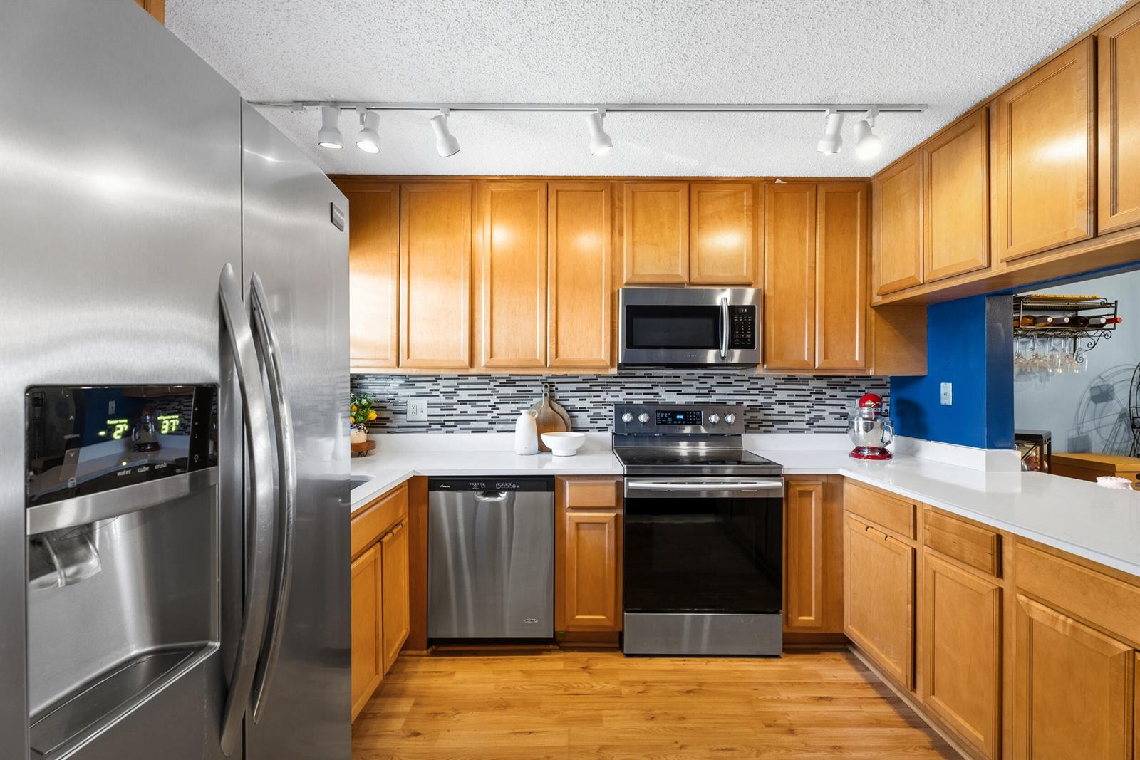A kitchen features wood cabinets, stainless steel appliances, a mosaic tile backsplash, and white countertops — 1201 SE Parkview Place # G4, Stuart FL 34994, STUART, FL