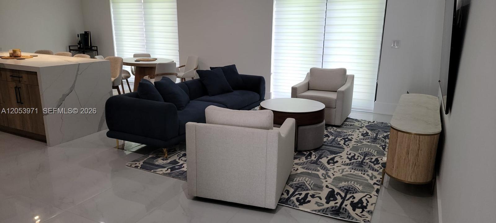 A living room features a dark blue sofa, two light-colored armchairs, and a patterned rug — 5901 SW 64th St, South Miami FL 33143, SOUTH MIAMI, FL