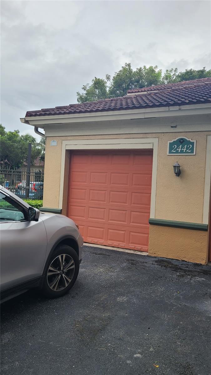 A tan building exterior features a salmon-colored garage door and the number 2442 — 2442 Centergate Dr # 101, Miramar FL 33025, MIRAMAR, FL