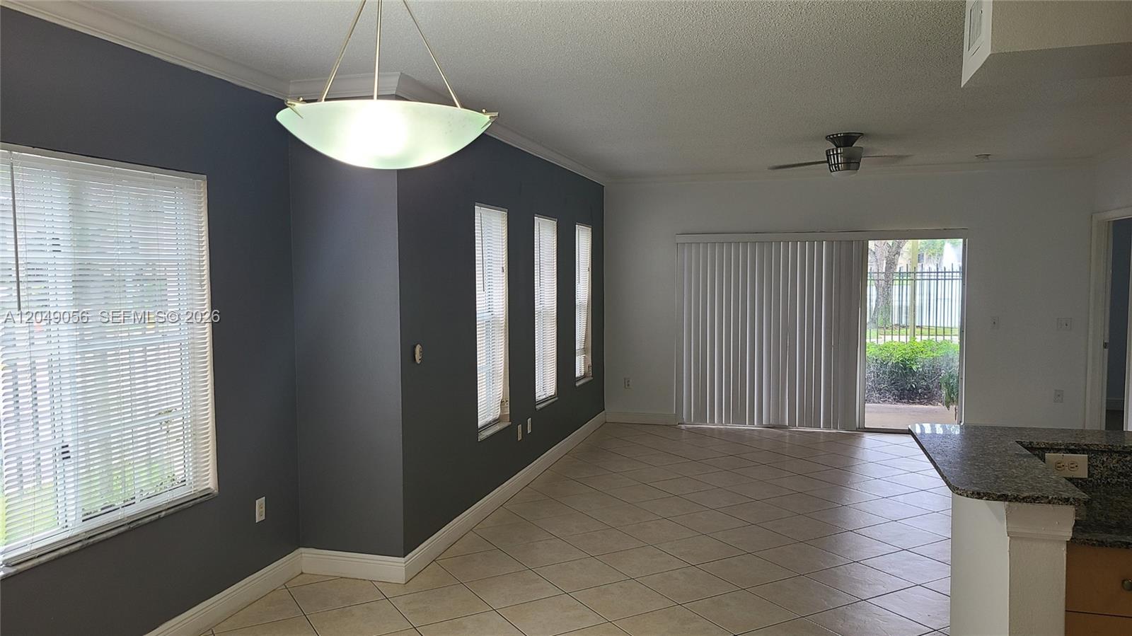 An open-concept dining area features dark gray walls, tile flooring, and a sliding glass door — 2442 Centergate Dr # 101, Miramar FL 33025, MIRAMAR, FL