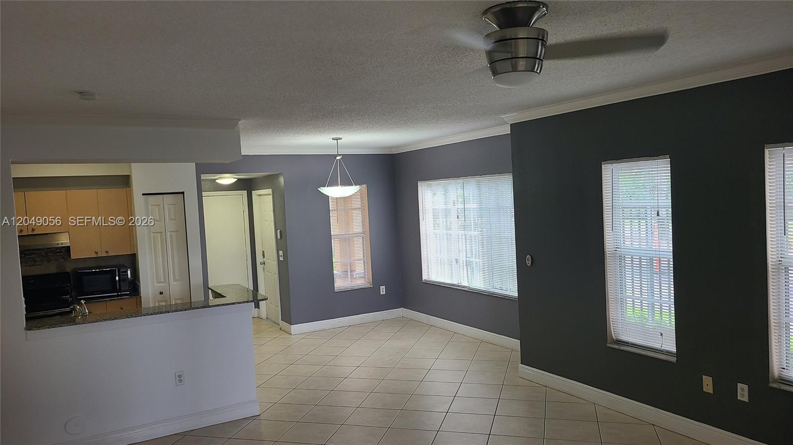 An open-concept living and dining area features gray walls, tile flooring, and a kitchen pass-through — 2442 Centergate Dr # 101, Miramar FL 33025, MIRAMAR, FL
