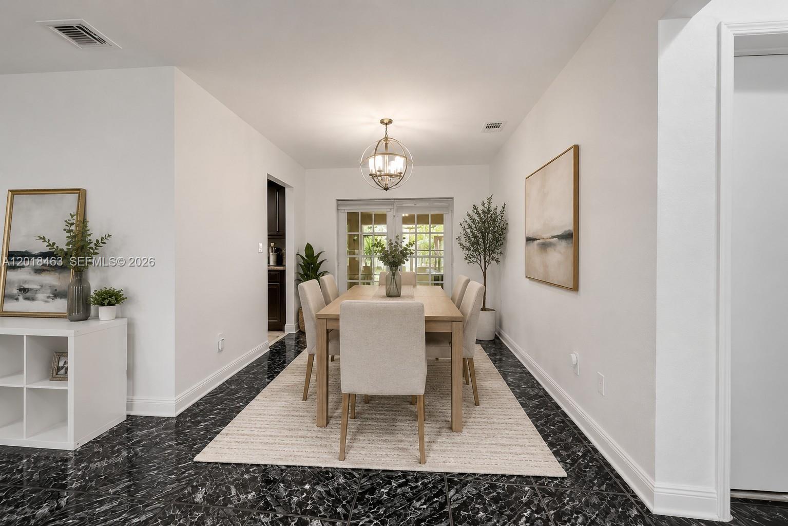 A dining room features a wooden table, upholstered chairs, a chandelier, and black marble flooring — 15725 SW 102nd Pl, Miami FL 33157, MIAMI, FL