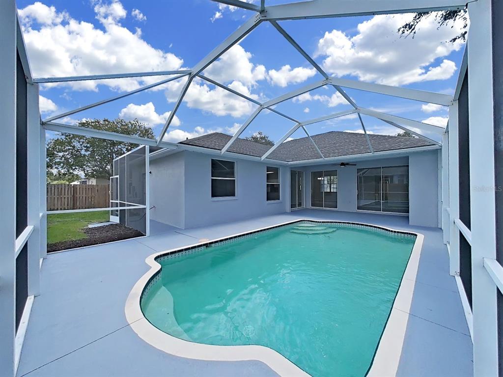 A swimming pool with a screened enclosure sits on a patio behind a light-colored house — 3313 MICHENER PLACE, PLANT CITY, FL