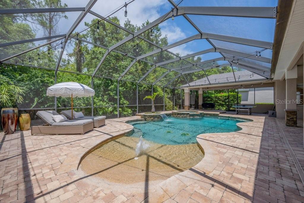 A screened-in patio features a swimming pool with a fountain, spa, and lounge chairs — 5967 JAEGERGLEN DRIVE, LITHIA, FL