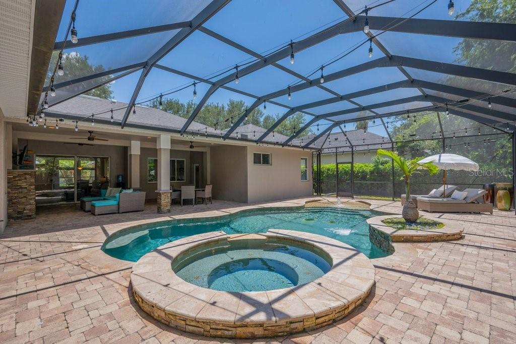 A screened-in patio features a swimming pool, a hot tub, and outdoor lounge furniture — 5967 JAEGERGLEN DRIVE, LITHIA, FL