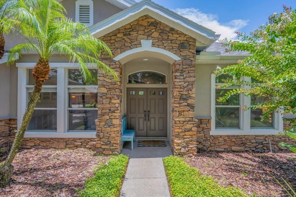 The exterior of a house features a stone-faced entryway with double doors and a walkway — 5967 JAEGERGLEN DRIVE, LITHIA, FL