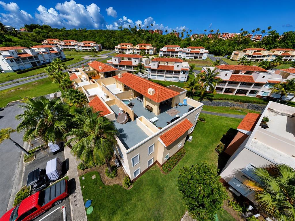An aerial view shows a multi-story residential complex with red-tiled roofs and palm trees — Palmas Drive COND. HARBOUR LAKES UNIT 26, HUMACAO, PR