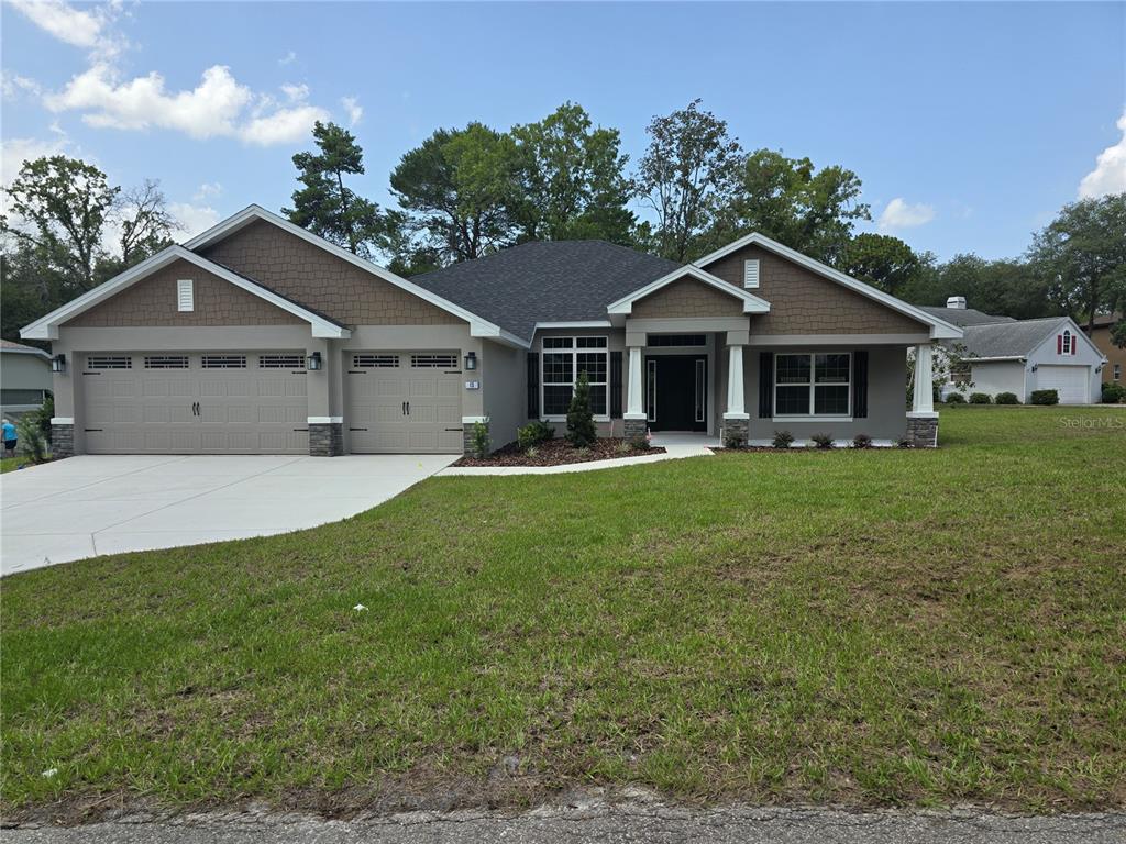 A single-story house features a three-car garage, stone accents, and a covered front entryway — 13 GERANIUM COURT, HOMOSASSA, FL