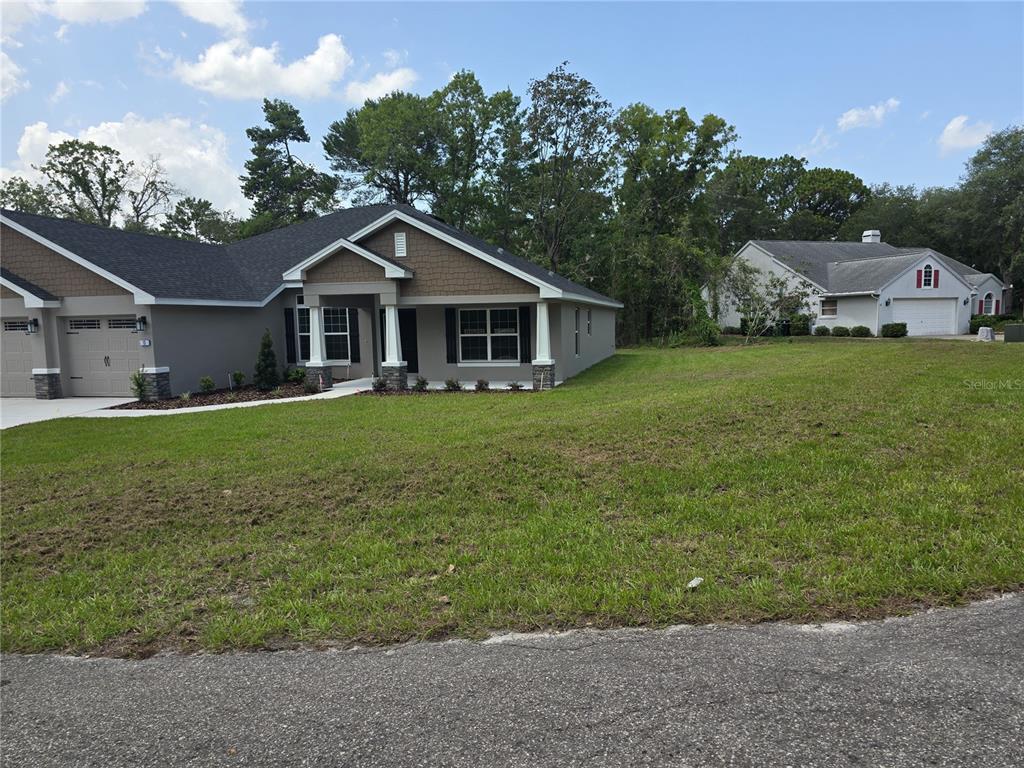 A modern single-story house with a gray exterior and a large grassy front yard — 13 GERANIUM COURT, HOMOSASSA, FL